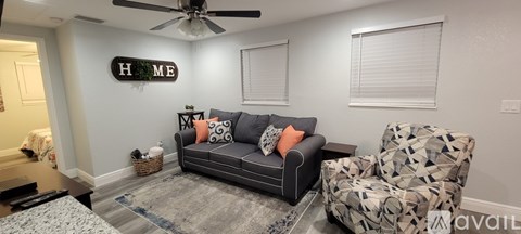 A living room with a grey couch and a patterned chair.