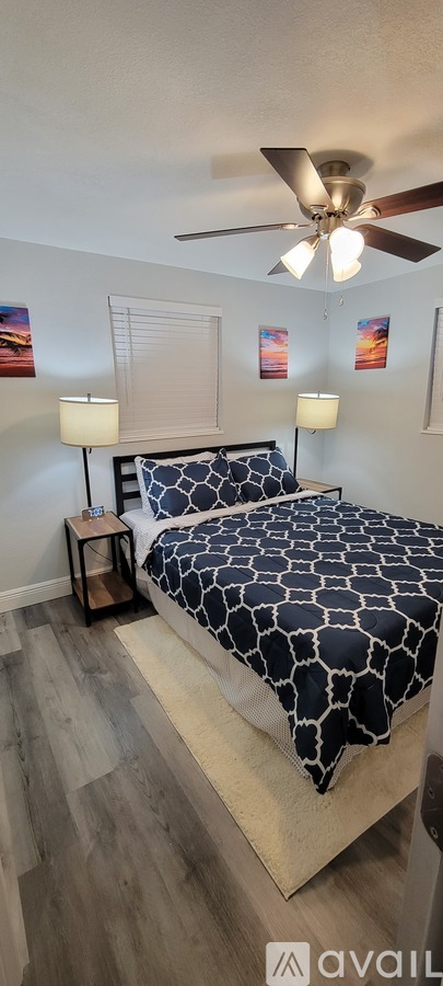 A bedroom with a bed, two lamps, and a ceiling fan.