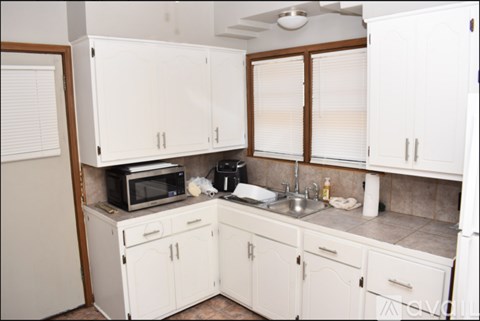 A kitchen with white cabinets and appliances.
