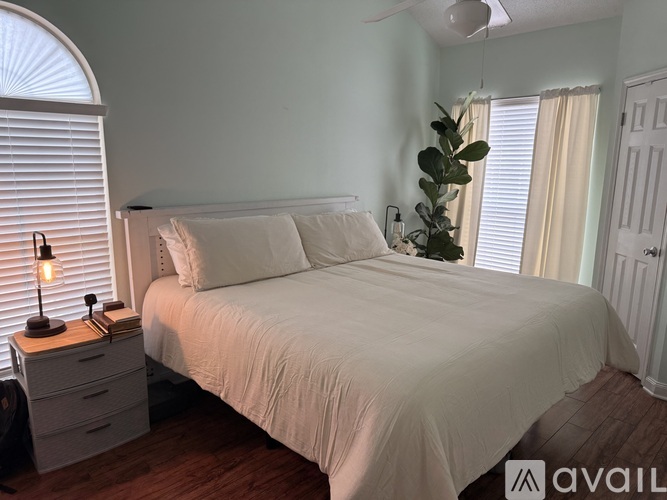 A bedroom with a bed, nightstand, and window.