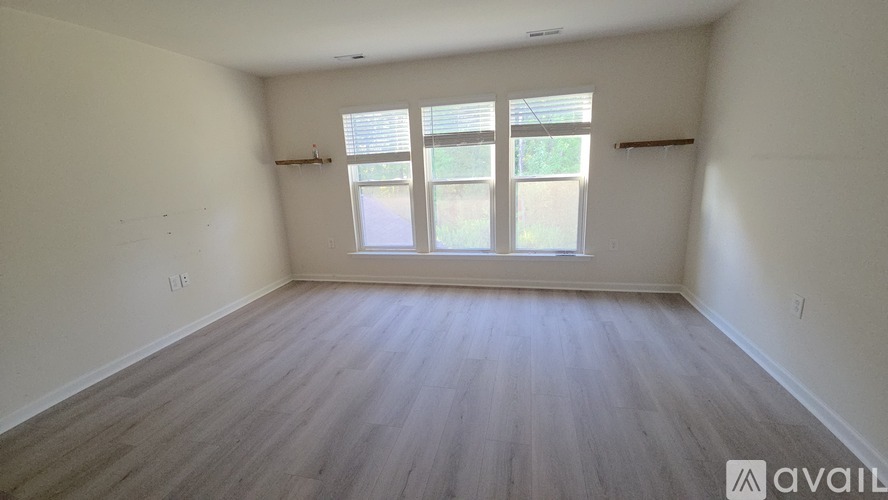 A room with wooden flooring and a window with blinds.