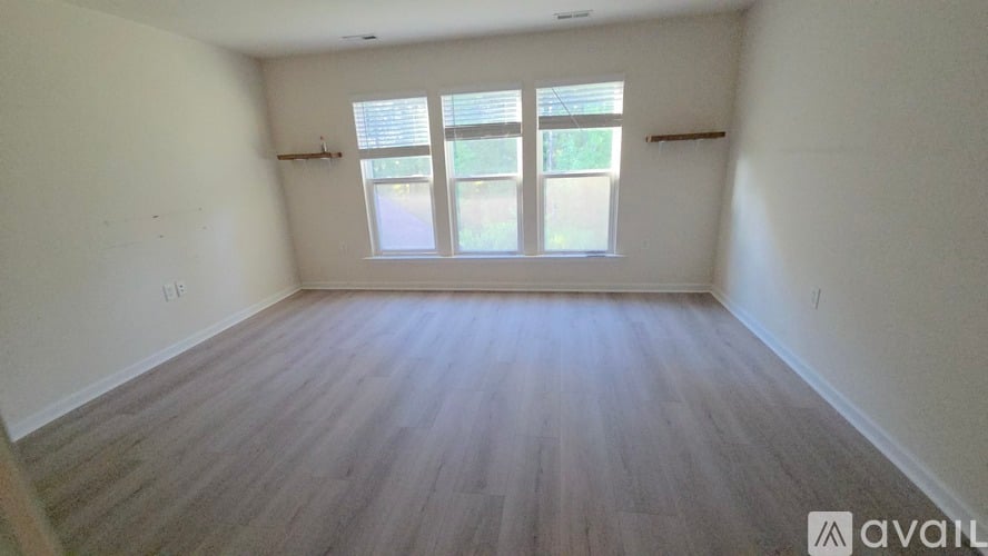 A room with wooden flooring and a window with blinds.