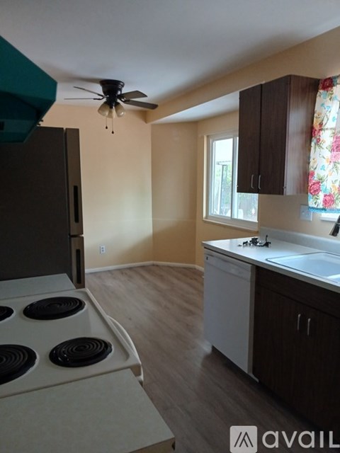 A kitchen with a white stove top oven and a fan on the ceiling.