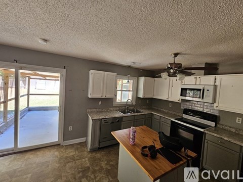 A kitchen with a wooden counter top and a ceiling fan.