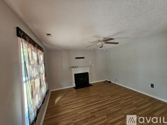 A living room with a fireplace and a ceiling fan.