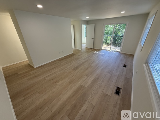 A spacious room with wooden flooring and white walls.