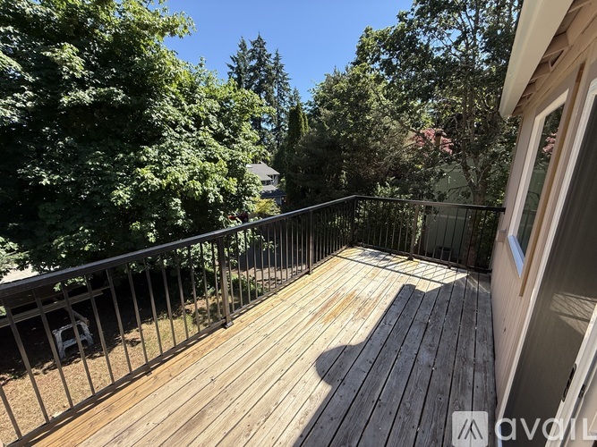 A wooden deck with a metal railing and trees in the background.