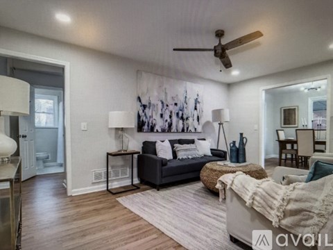 A living room with a couch, a rug, and a painting on the wall.