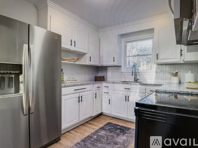 A kitchen with white cabinets and a stainless steel refrigerator.