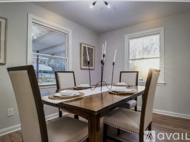 A dining room with a table set for two and a window letting in light.