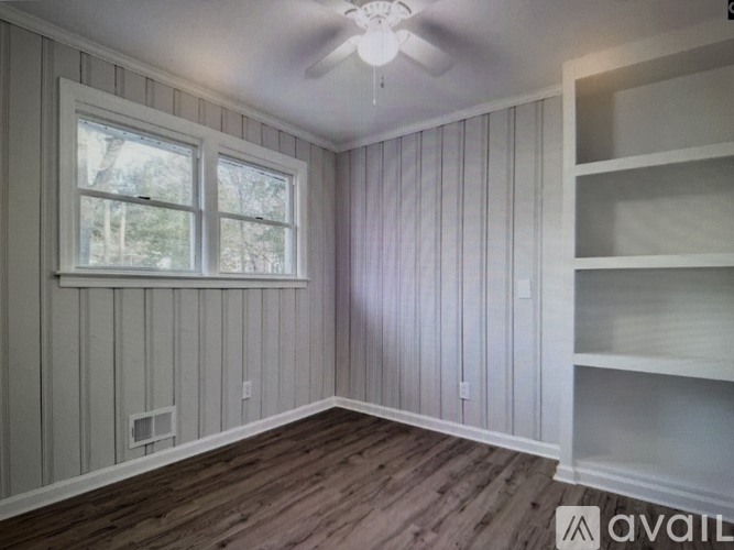 A room with wooden floors and a window with a view of trees.