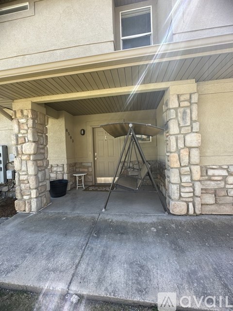 A stone pillar entrance to a home with a tripod light stand in front.