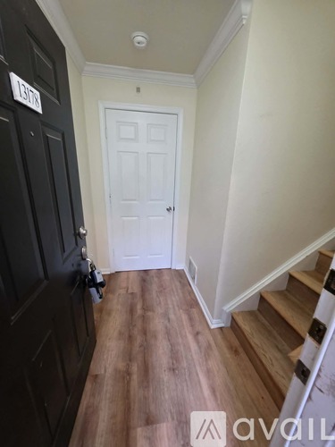 A hallway with a black door and a white door at the end.
