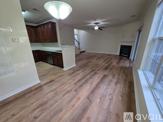 A spacious living room with wooden flooring and a ceiling fan.
