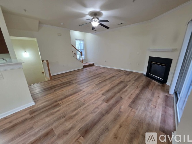 A spacious room with wooden flooring and a fireplace.