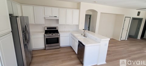A kitchen with white cabinets and a wooden floor.