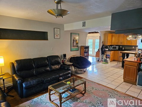A living room with a black leather couch and a coffee table.