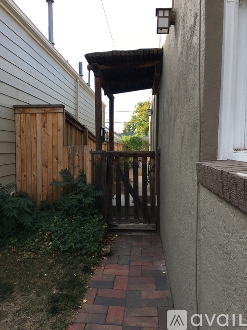 A small alley with a wooden gate and brick walkway.