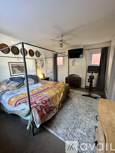 A bedroom with a bed, a ceiling fan, and a window with curtains.