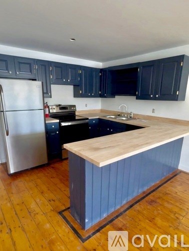 A kitchen with a wooden island and dark cabinets.