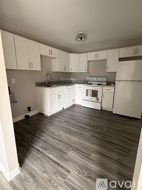 A kitchen with white cabinets and a grey floor.