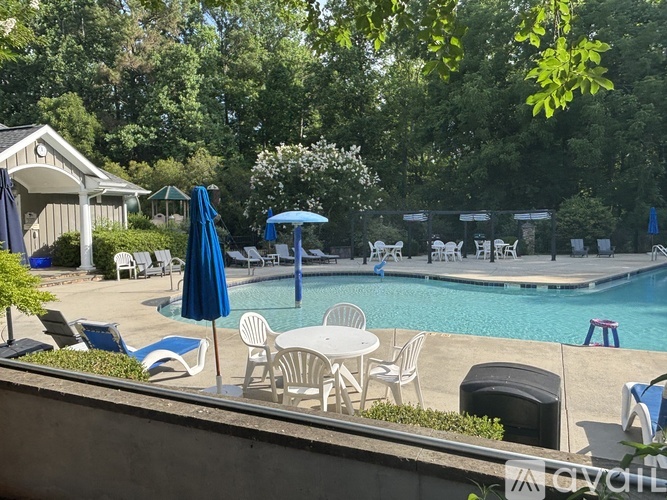 A pool area with chairs and umbrellas.
