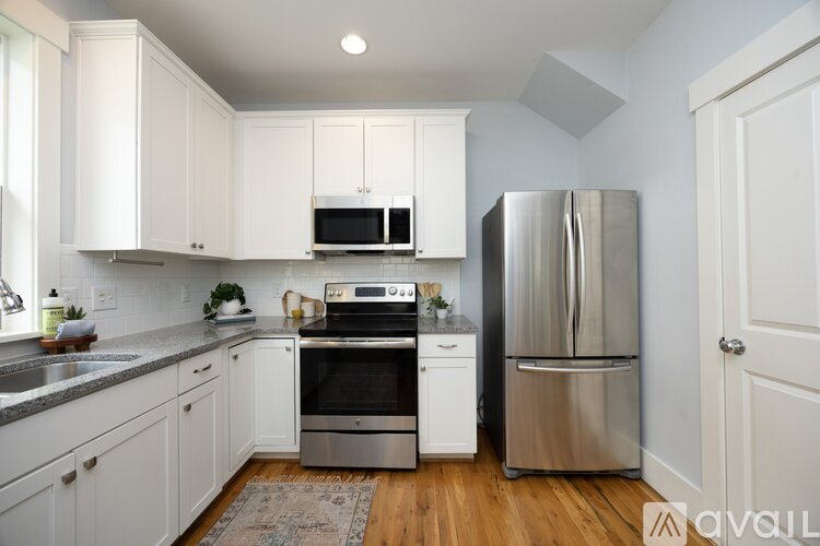 A kitchen with white cabinets and a stainless steel refrigerator.