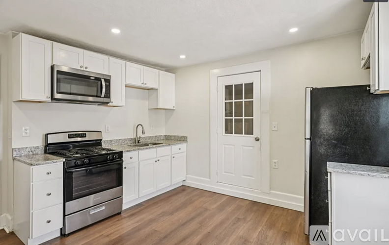 A kitchen with white cabinets and a black refrigerator.