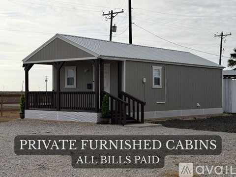 A gray building with the words "PRIVATE FURNISHED CABINS ALL BILLS PAID" on a sign in front of it.