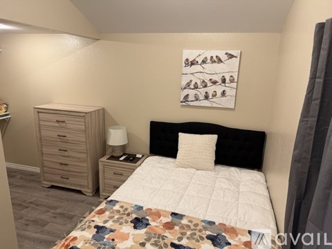 A bedroom with a bed, nightstand, and a painting on the wall.