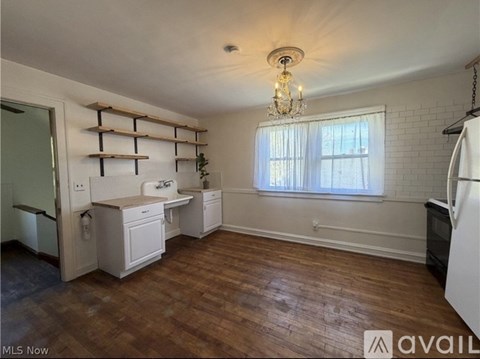 A kitchen with white cabinets and a wooden shelf above the sink.