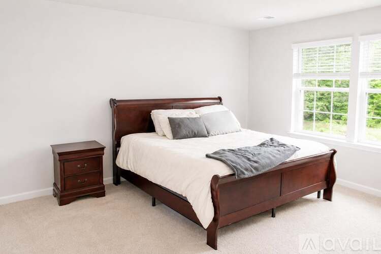 A bedroom with a bed, nightstand, and window.