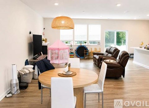 A living room with a round table and chairs, a television, and a pink canopy bed in the background.