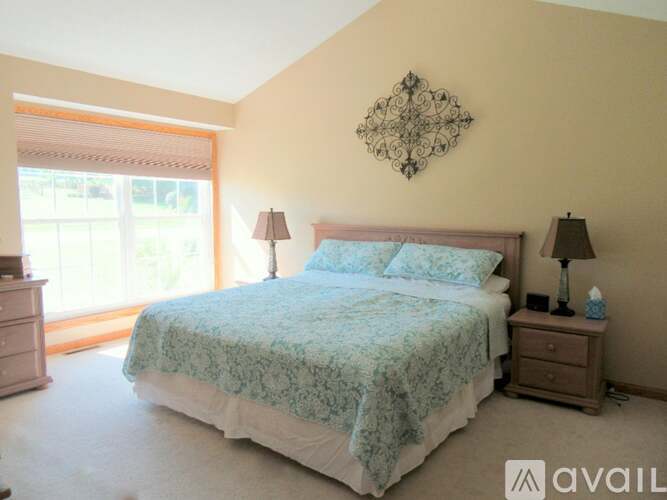 A bedroom with a bed, nightstands, and a wall decoration.