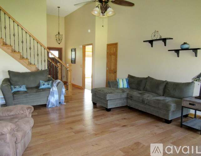 A living room with a staircase and a ceiling fan.