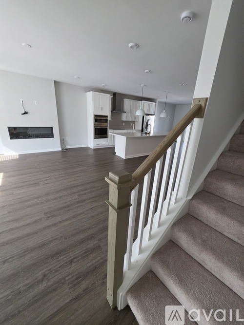 A staircase with a wooden banister leads to a kitchen and living room.