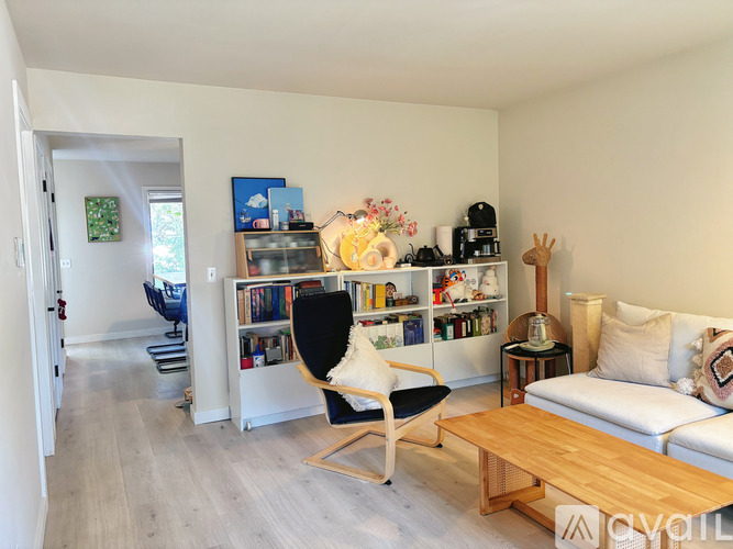 A living room with a white couch, a black chair, and a wooden coffee table.