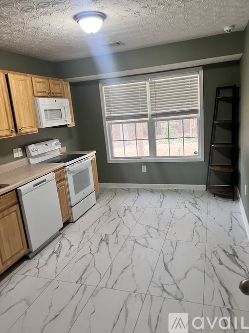 A kitchen with white appliances and wooden cabinets.