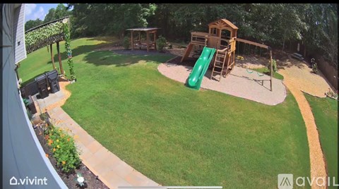 A backyard with a green slide and a wooden playhouse.