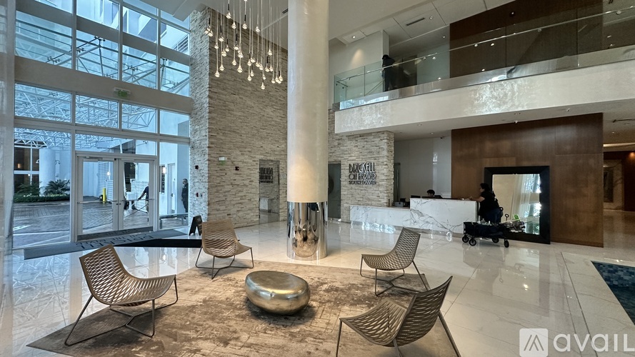 A spacious lobby with a stone pillar and a large window overlooking a parking lot.