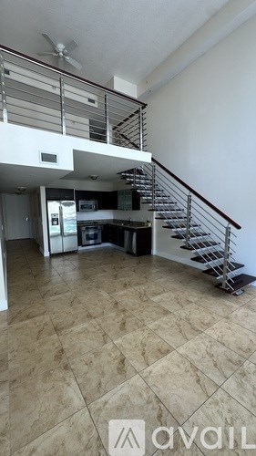 A spacious room with a staircase and a kitchen area.
