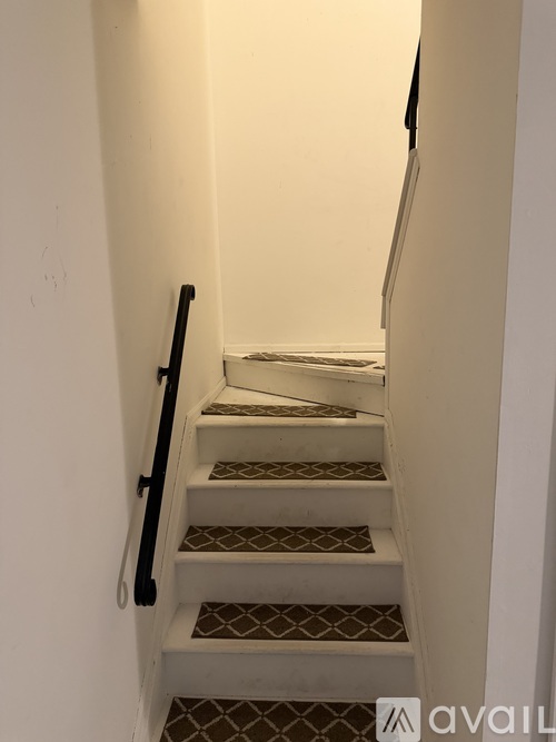 A staircase with a black handrail and a patterned tread.