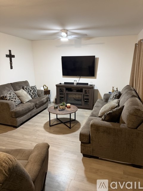 A living room with a grey couch, a black coffee table, and a television on the wall.
