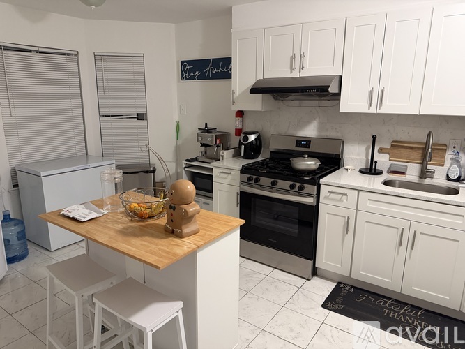 A kitchen with white cabinets and a wooden island.