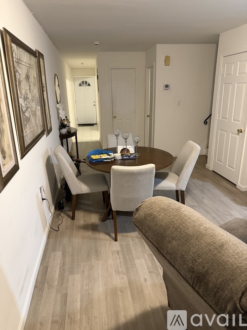 A dining room with a table set for four and chairs around it.