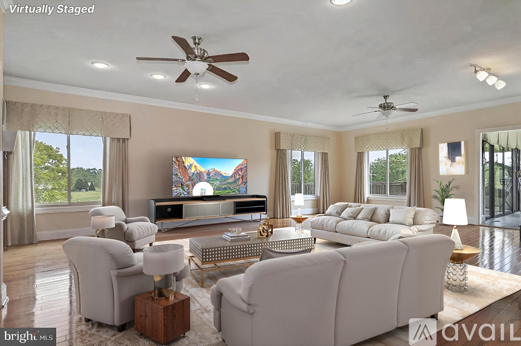 A living room with a large screen TV and a white sofa.