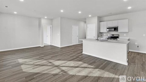 A spacious kitchen with white cabinets and a wooden floor.