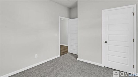 A room with a carpeted floor and two white doors.