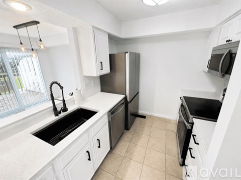 A kitchen with white cabinets and black appliances.