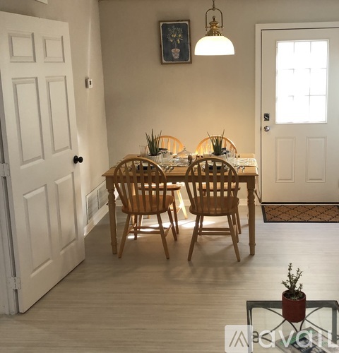 A dining room with a table set for two and a potted plant on the table.